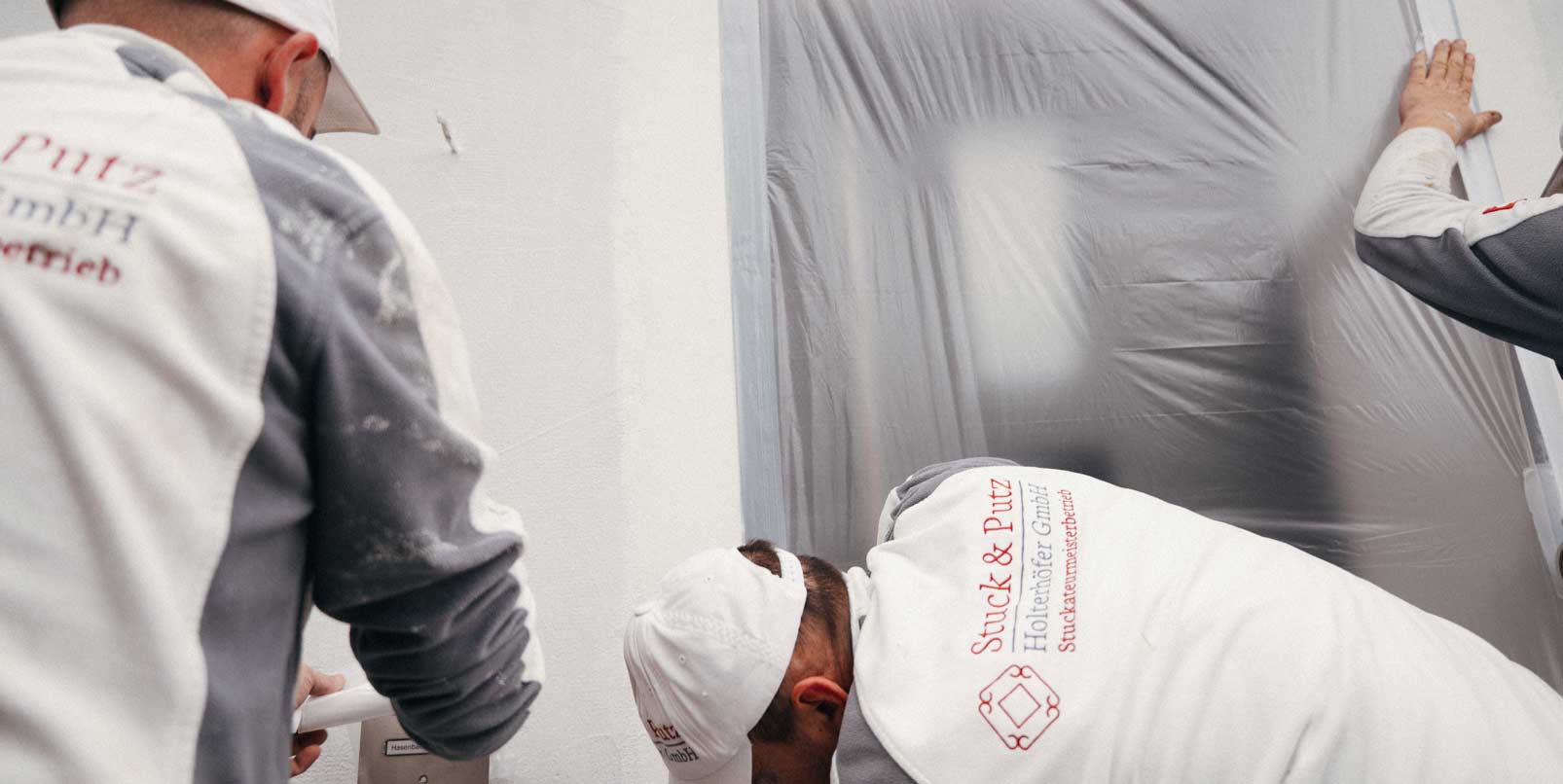 Das Team von Stuck & Putz klebt Teile einer Wand ab
